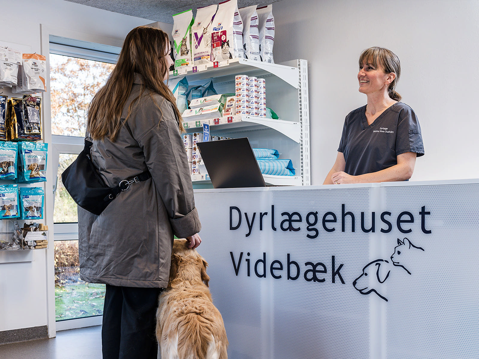 Kvinde med hund ved reception i dyrlægeklinik